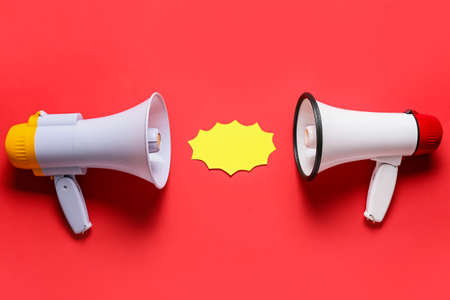 Modern megaphones and speech bubble on color backgroundの写真素材