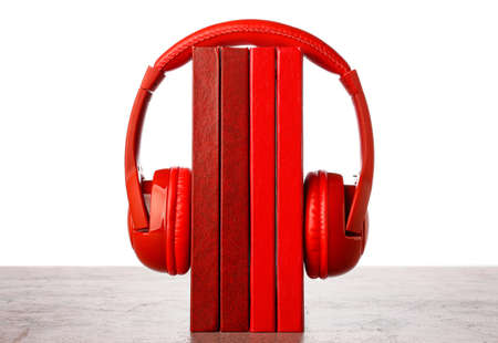 Modern headphones with books on table against white background