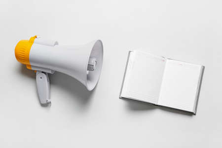 Modern megaphone and notebook on light background