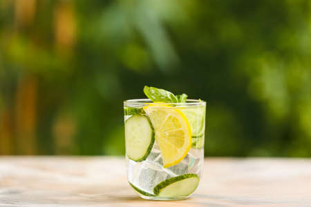 Glass of cucumber lemonade on table outdoors