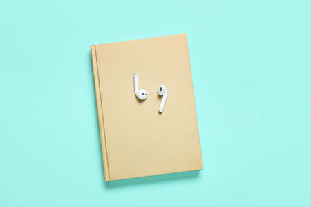Modern earphones with book on color backgroundの写真素材