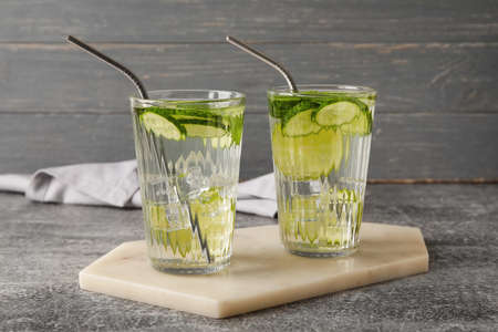 Glasses with cucumber lemonade on gray background