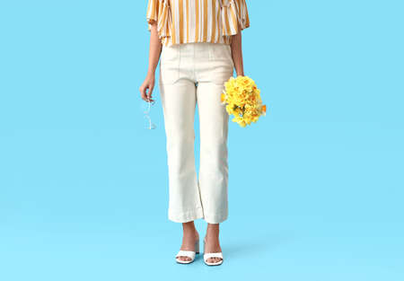 Beautiful young woman with narcissus bouquet on color backgroundの写真素材