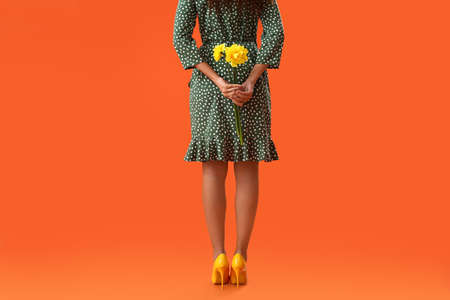 Beautiful young woman with narcissus bouquet on color backgroundの写真素材