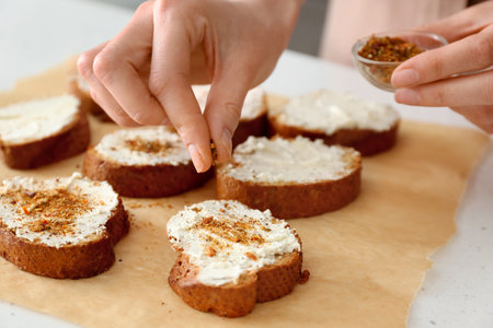 Female chef adding spices to toasts on kitchen table, closeupの写真素材