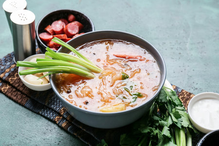Bowl with tasty sauerkraut soup and ingredients on tableの写真素材