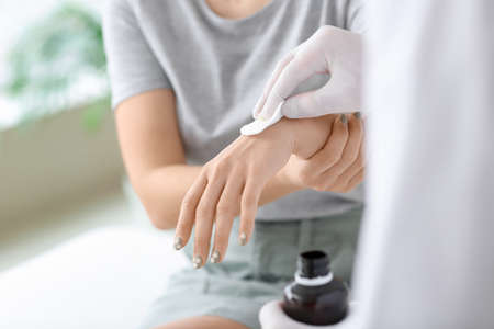 Doctor disinfecting hand of young woman in clinicの写真素材