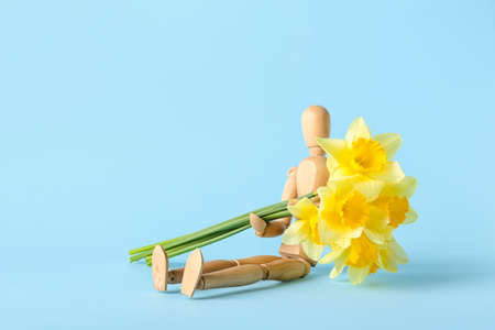 Wooden mannequin with beautiful daffodils on color backgroundの写真素材