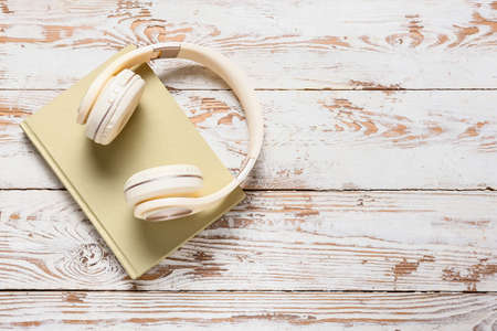 Modern headphones and book on light wooden backgroundの写真素材