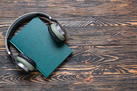 Modern headphones and book on wooden backgroundの写真素材