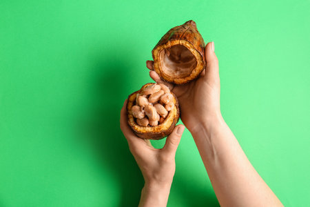 Woman holding fresh cocoa fruit on color backgroundの写真素材