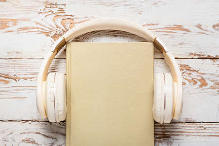 Modern headphones and book on light wooden backgroundの写真素材