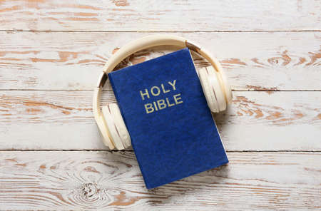 Holy Bible and modern headphones on light wooden backgroundの写真素材
