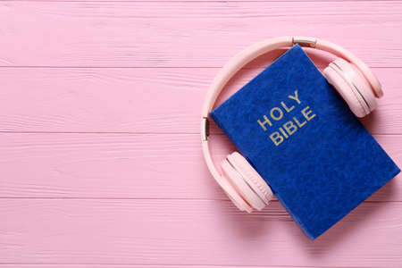 Holy Bible and modern headphones on color wooden backgroundの写真素材