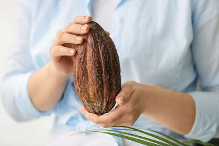 Woman holding fresh cocoa fruit, closeup