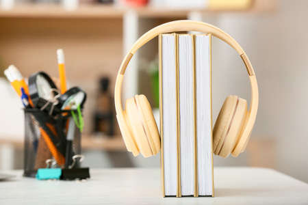 Modern headphones and books on table in roomの写真素材