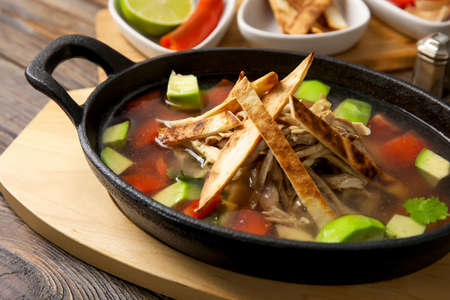 Baking dish with tasty Sopa de Lima soup on table, closeupの写真素材