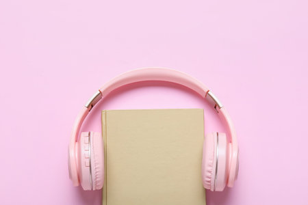 Modern headphones and book on color backgroundの写真素材