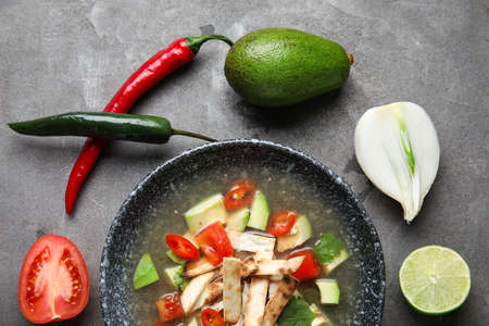 Composition with tasty Sopa de Lima soup on dark background
