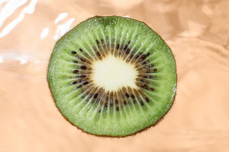 Slice of tasty kiwi into water on color background, closeupの写真素材