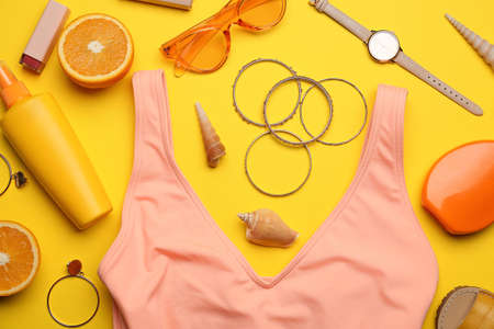 Set of beach accessories and orange on color background, closeup