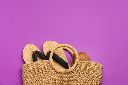 Stylish bag with flip-flops and coconut on color backgroundの写真素材
