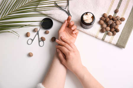 Female hands with jar of shea butter, nuts, tools for manicure and towel on white backgroundの写真素材