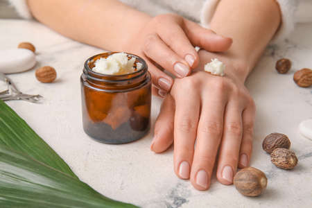 Woman applying shea butter onto hands on light backgroundの写真素材