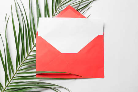 Envelope with blank card and palm leaf on white backgroundの写真素材