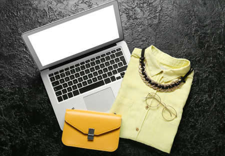 Female shirt, stylish accessories and laptop on dark backgroundの写真素材