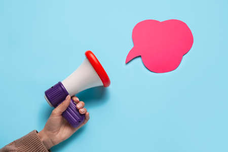Woman with toy megaphone and speech bubble on color background