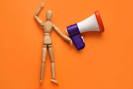 Wooden mannequin with toy megaphone on color backgroundの写真素材