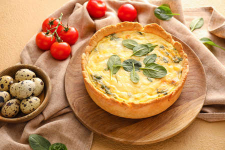 Tasty spinach tart, quail eggs and tomatoes on color backgroundの写真素材