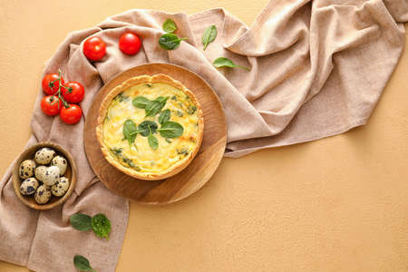 Tasty spinach tart, quail eggs and tomatoes on color background