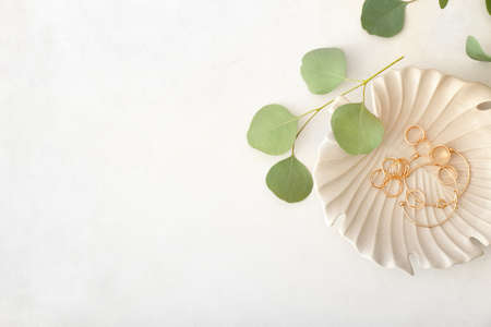 Plate with jewelry and eucalyptus leaves on light backgroundの写真素材