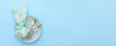 Beautiful table setting for Easter celebration on blue background with space for textの写真素材