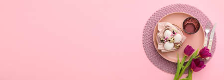 Beautiful table setting for Easter celebration on pink background with space for textの写真素材