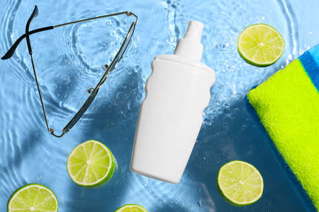 Beach accessories and slices of lime on color background with water drops