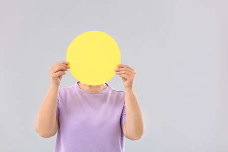 Mature woman with blank paper sheet on light backgroundの写真素材