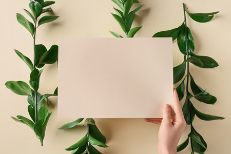 Female hand with blank card and plant branches on color background, closeupの写真素材