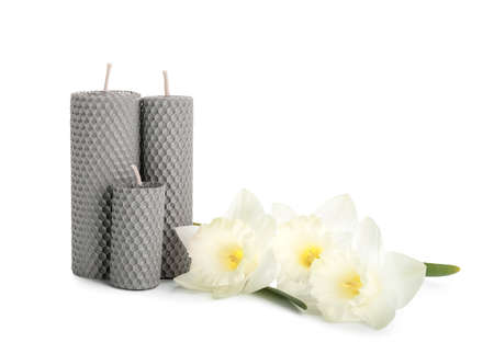 Wax candles and beautiful Narcissus flowers on white backgroundの写真素材