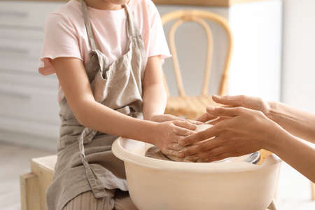 Little girl with her mother making ceramic pot at homeの写真素材