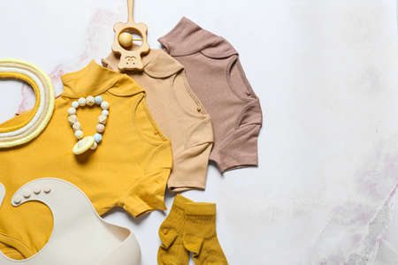 Set of baby clothes, bib and toys on light backgroundの写真素材