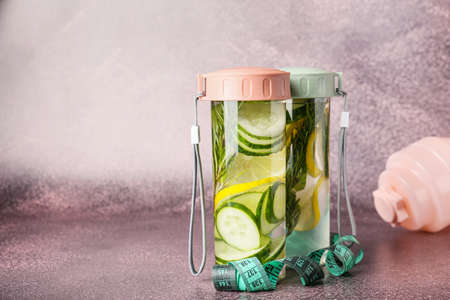 Bottles with cucumber lemonade and measuring tape on grunge backgroundの写真素材