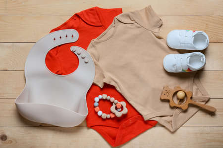 Baby clothes, shoes, bib and toys on wooden backgroundの写真素材