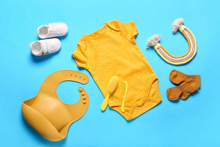 Baby clothes, shoes, toy and accessories on color background