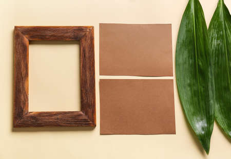 Composition with blank cards, empty picture frame and green leaves on color backgroundの写真素材