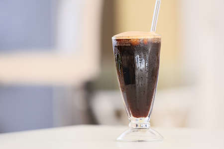 Glass of tasty iced coffee on table