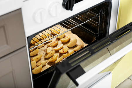Electric oven with potato in kitchen, closeupの写真素材