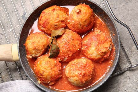 Frying pan with delicious meatballs and melted cheese on table